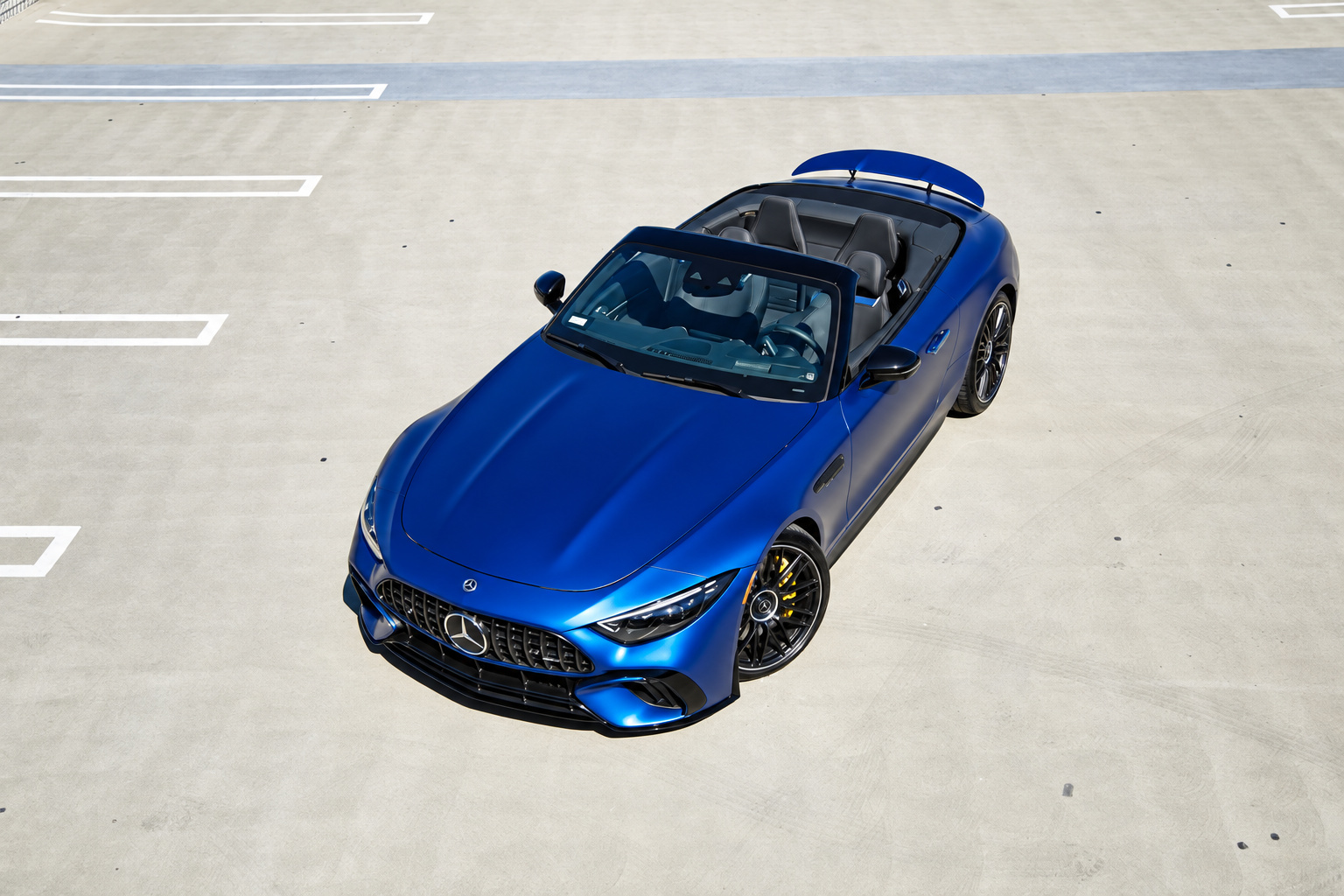 High angle front three-quarter of the blue Mercedes-Benz AMG SL rental, roof down, long hood and 2+2 cabin