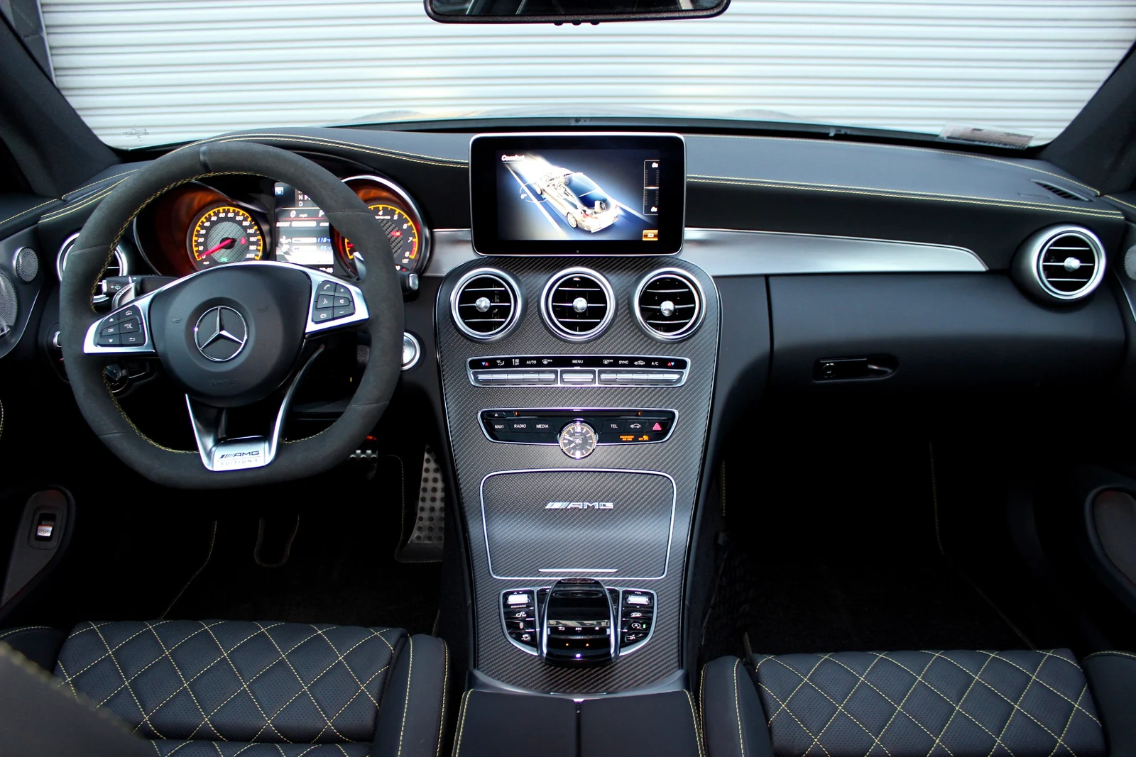 Dashboard of the grey Mercedes-Benz AMG C63 rental, diamond-quilted seats with yellow stitching and turbine vents