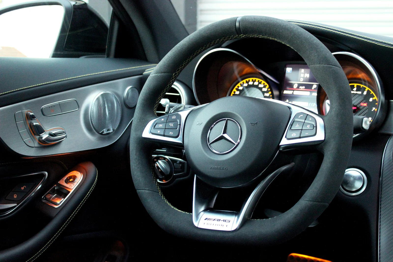 Flat-bottom Alcantara steering wheel in the Mercedes-Benz AMG C63 rental with the yellow 12 o'clock marker