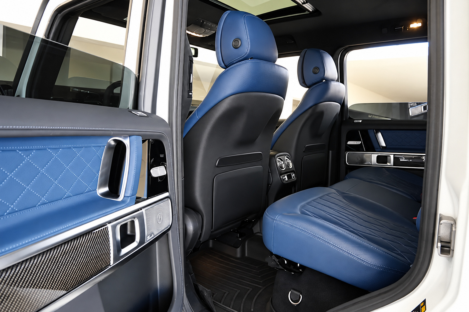 Rear seats of the white G63 in yacht blue leather, diamond-quilted door panel and carbon trim through the open door