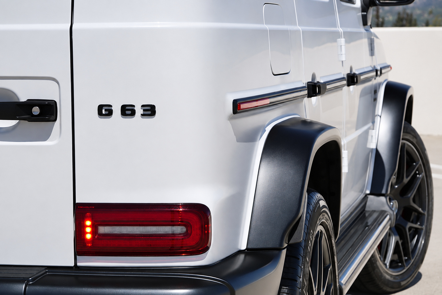 G63 badge on the white rear fender, black wheel arch flare and tail lamp close up