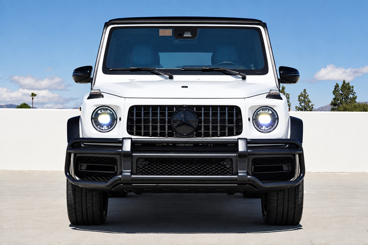 Head-on view of the white Mercedes-AMG G63, round headlamps, AMG grille and black lower bumper