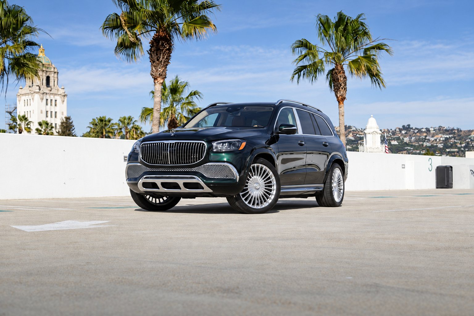 Emerald Green Mercedes-Maybach GLS 600 on a Beverly Hills rooftop, front three-quarter with the City Hall tower behind