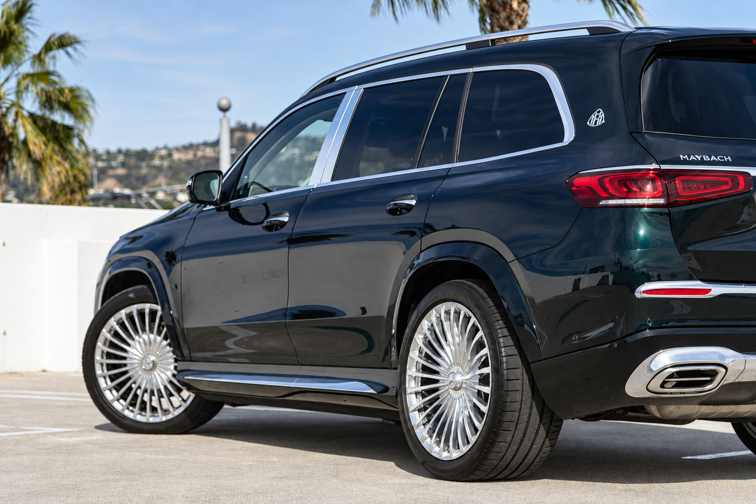 Rear three-quarter of the dark green Maybach GLS 600, chrome multi-spoke wheels and the Maybach badge on the rear pillar