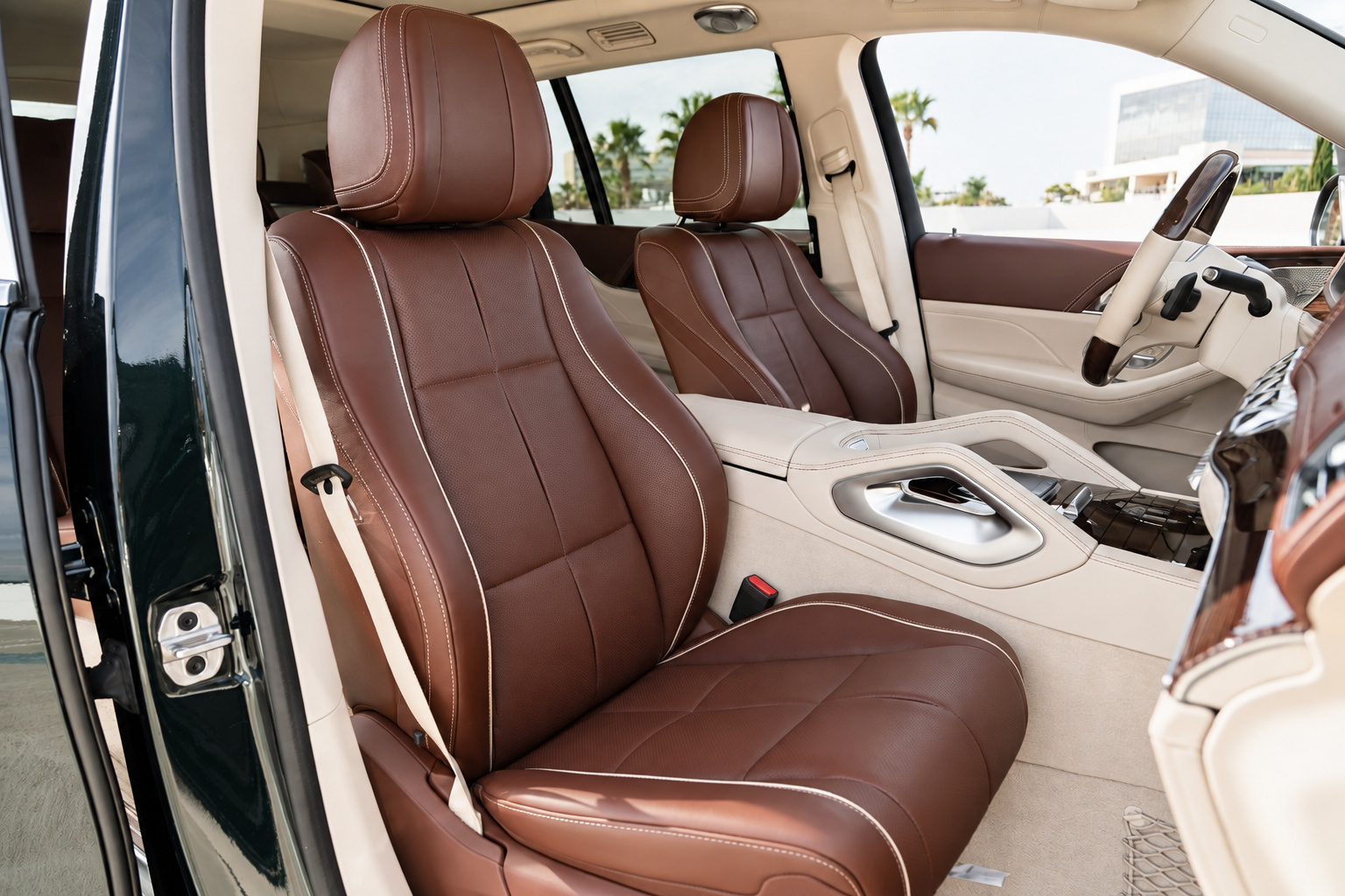Front seats of the Maybach GLS 600 in mahogany brown and cream leather, shot through the open driver's door