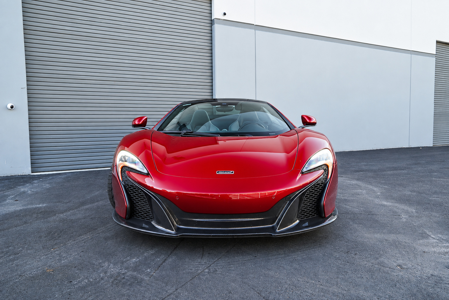 Head-on view of the red McLaren 650S Spider, swept headlights and carbon front splitter