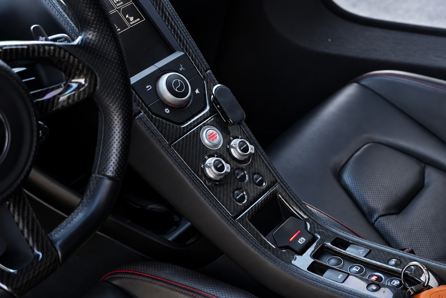 Center console of the red McLaren 650S Spider with carbon fiber trim, drive mode dials and red stitched leather