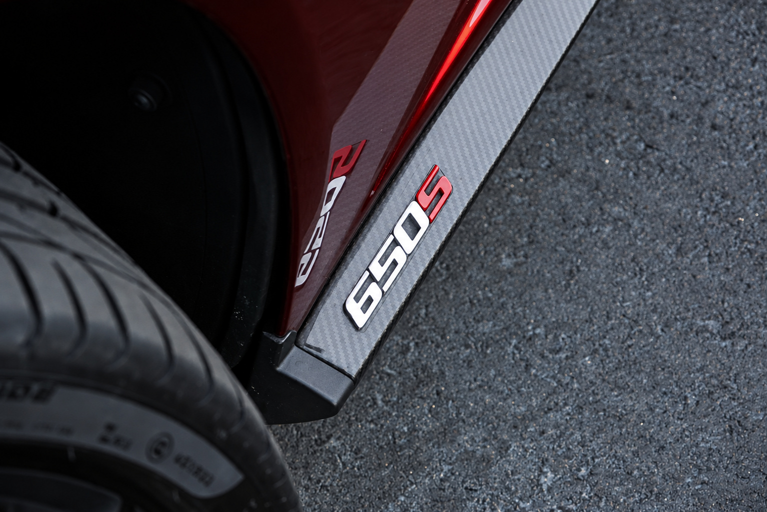 Carbon fiber sill plate with the 650S badge beside the rear tire of the Volcano Red McLaren 650S Spider