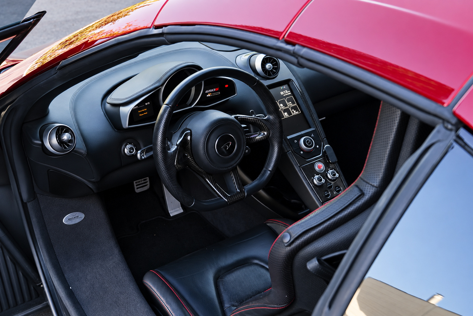 Driver's view of the McLaren 650S Spider cabin, black leather, red stitching and the portrait touchscreen
