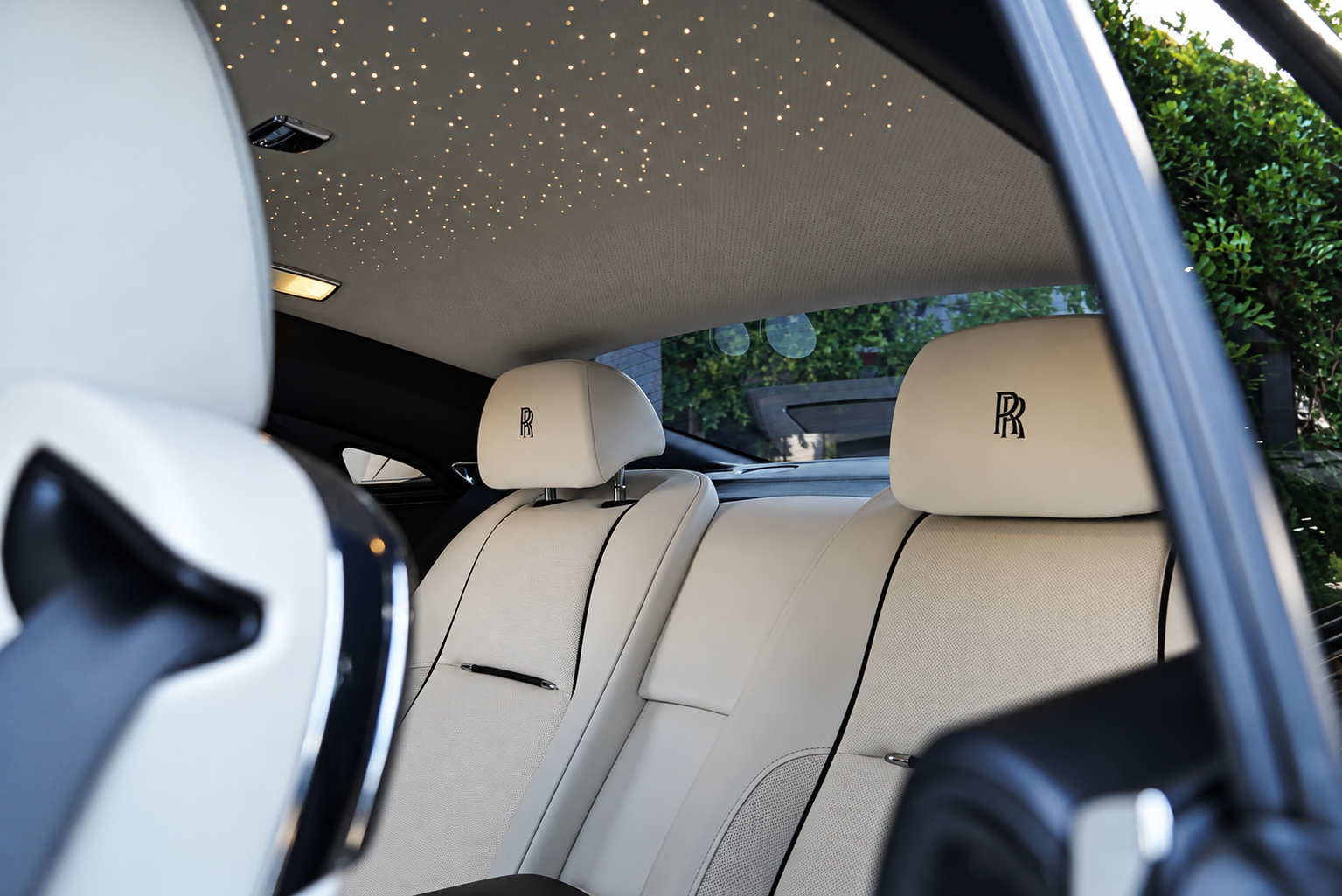 Starlight headliner above the ivory rear seats of the black Rolls Royce Wraith, RR on the headrests