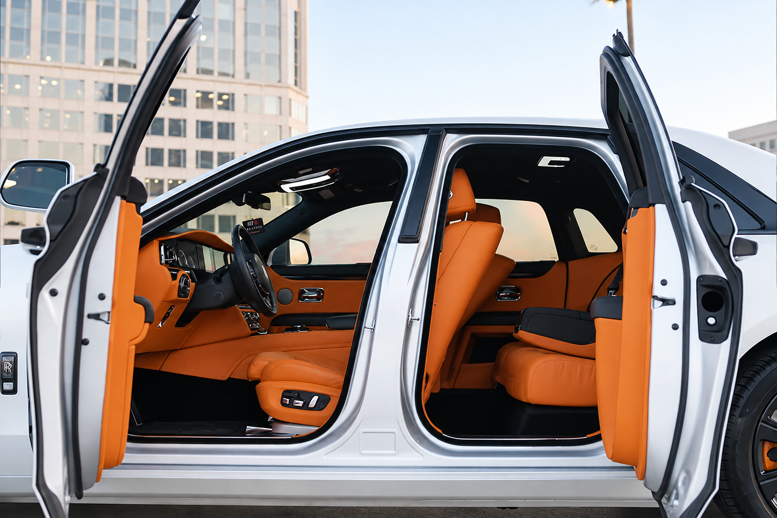 Rolls Royce Ghost with all 4 coach doors open showing the orange leather cabin, rooftop and towers behind