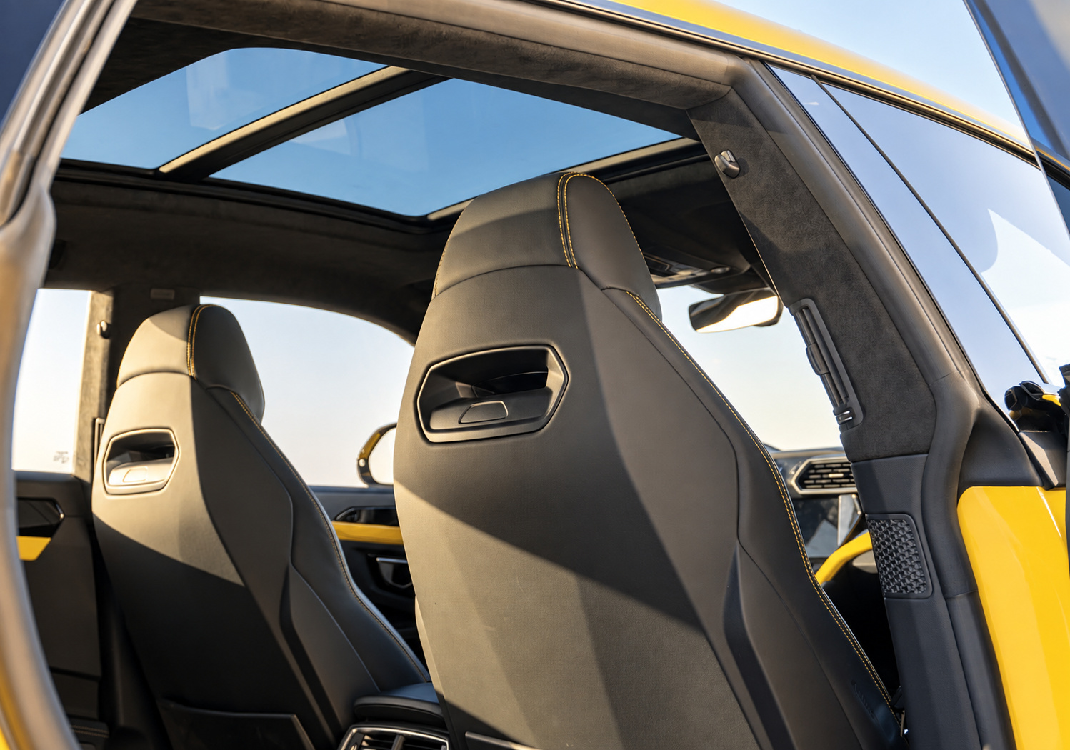 Black front seats with yellow stitching inside the Urus Widebody under the panoramic glass roof