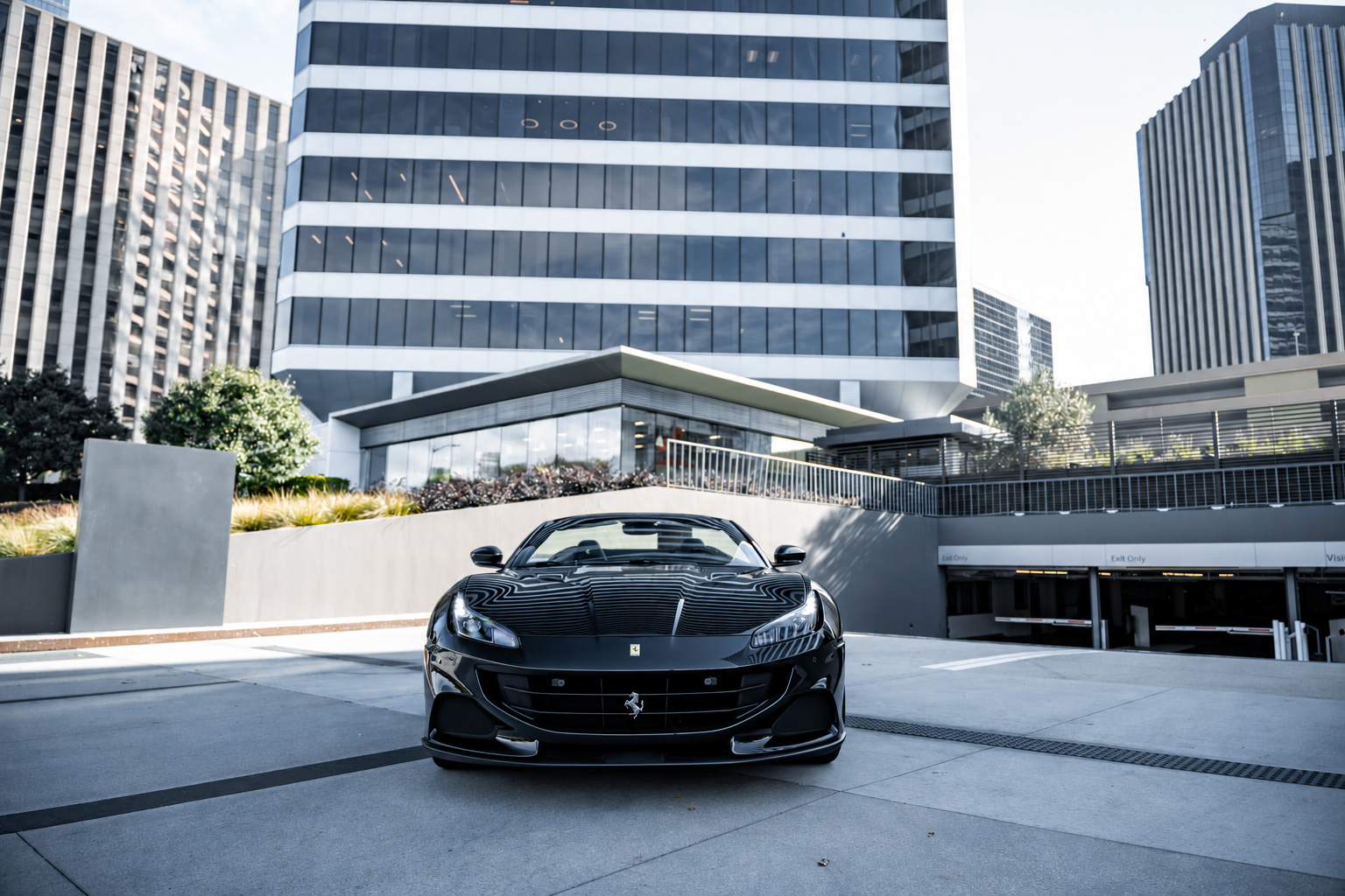 Head-on view of the black Portofino with the roof down, Century City office towers rising behind it
