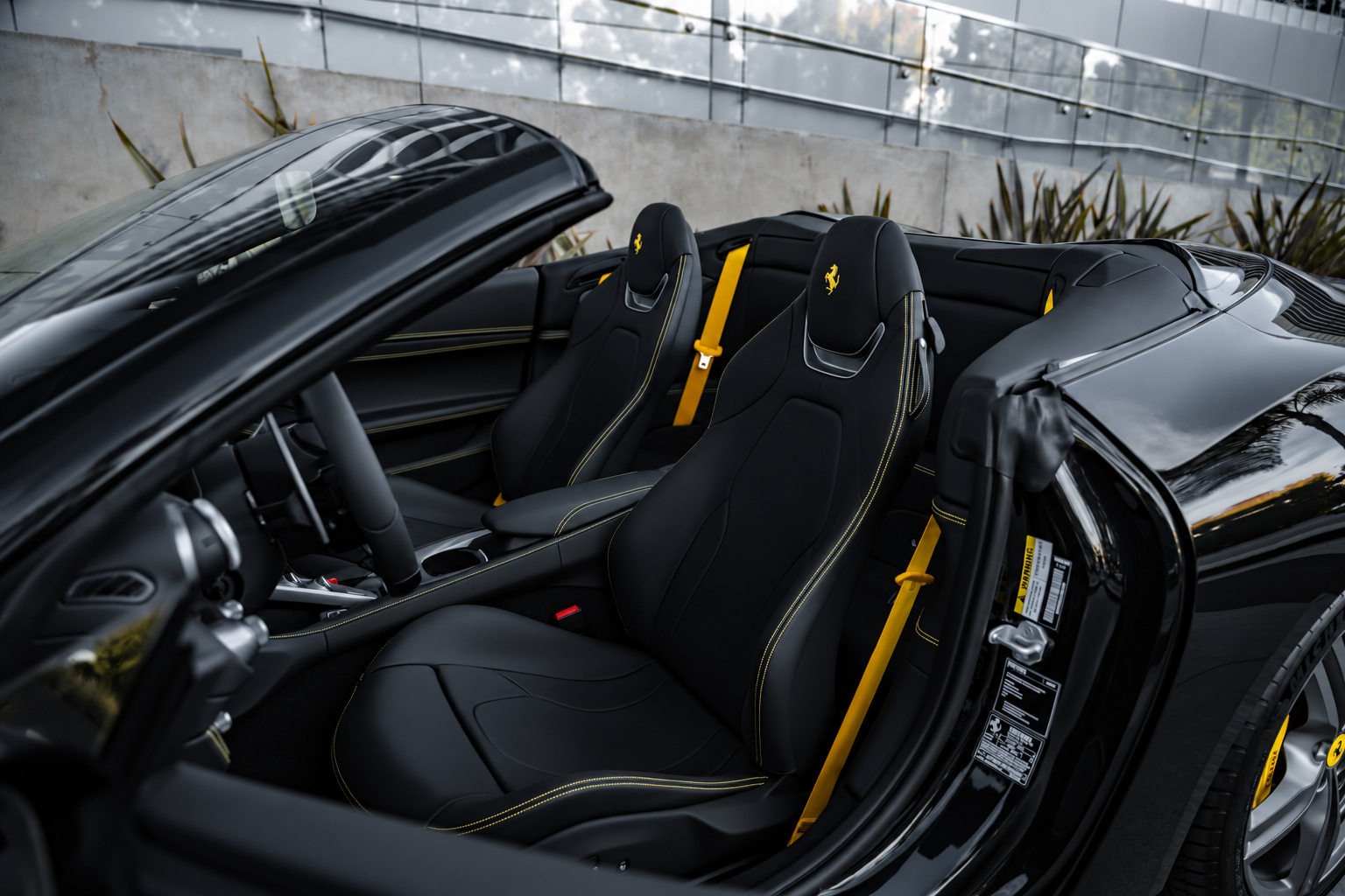 Open cabin of the black Portofino from the side, black seats with yellow stitching and yellow seatbelts