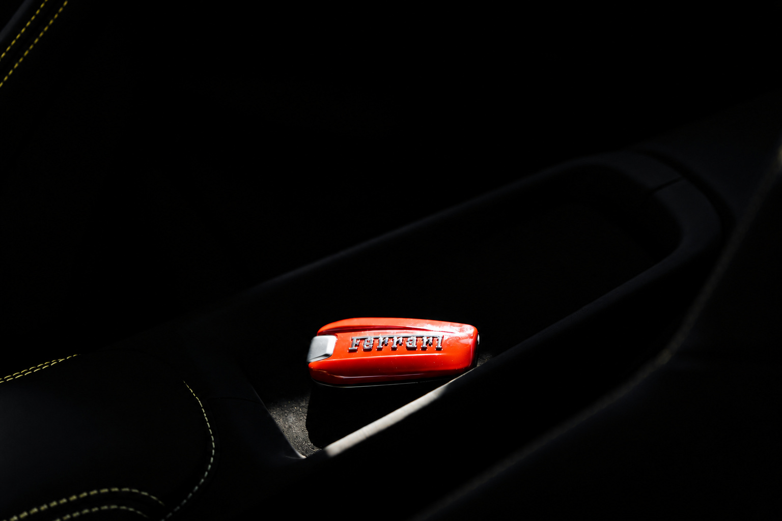 Red Ferrari key sitting in the black leather door pocket of the Portofino