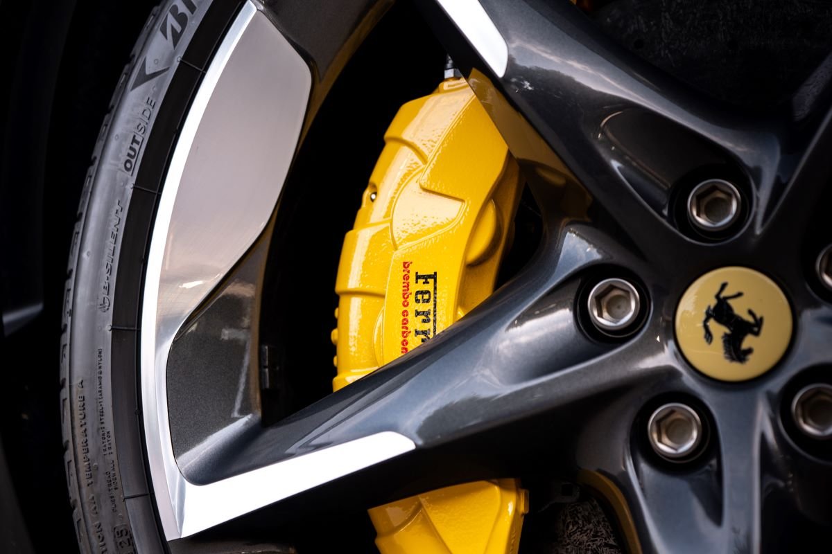 Close up of the yellow brake caliper inside the dark 5-spoke wheel of the Ferrari Purosangue