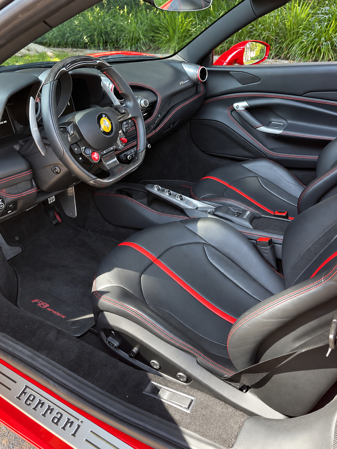 Black leather seat of the F8 Spider with red piping, the Ferrari sill plate and the carbon steering wheel