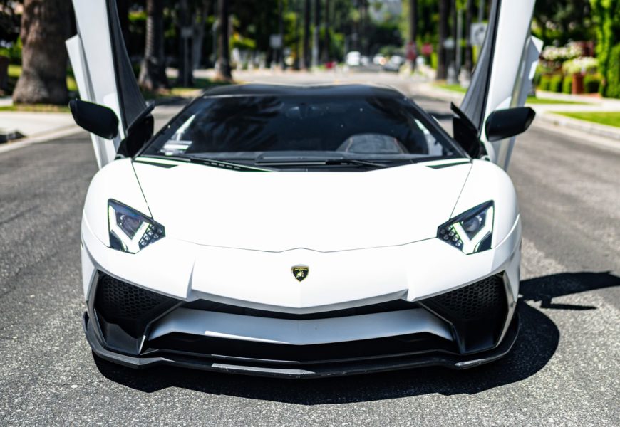 Head-on view of the white Aventador SV with both doors raised in the middle of a Beverly Hills residential street