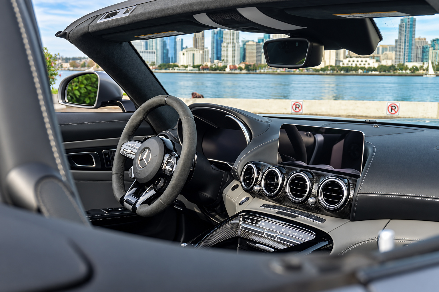 Driver's view of the black AMG GT C Roadster cabin, suede-grip AMG steering wheel, bay and skyline ahead