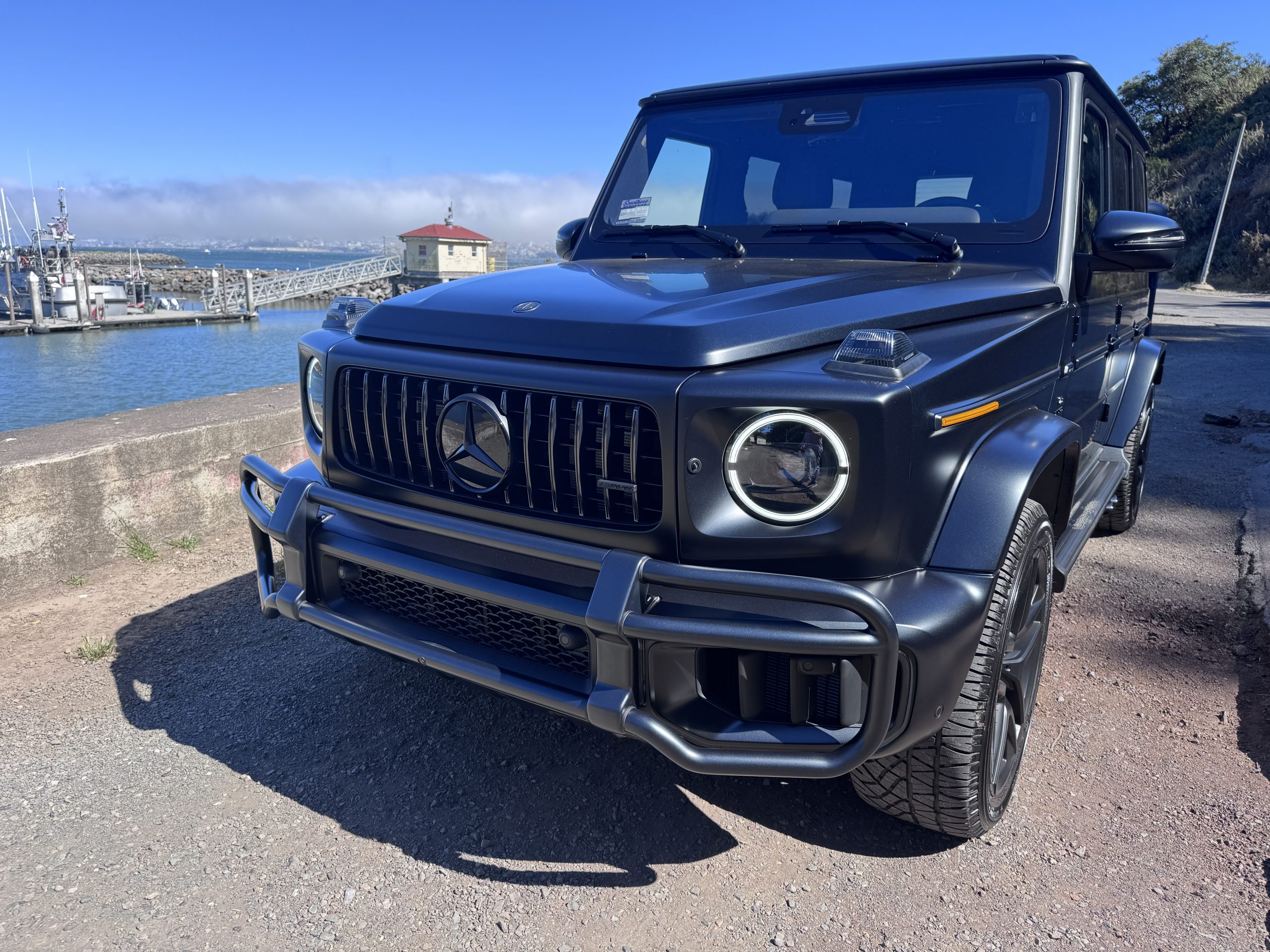 Close front view of the matte black G63 showing the Panamericana grille, round headlights and black brush guard