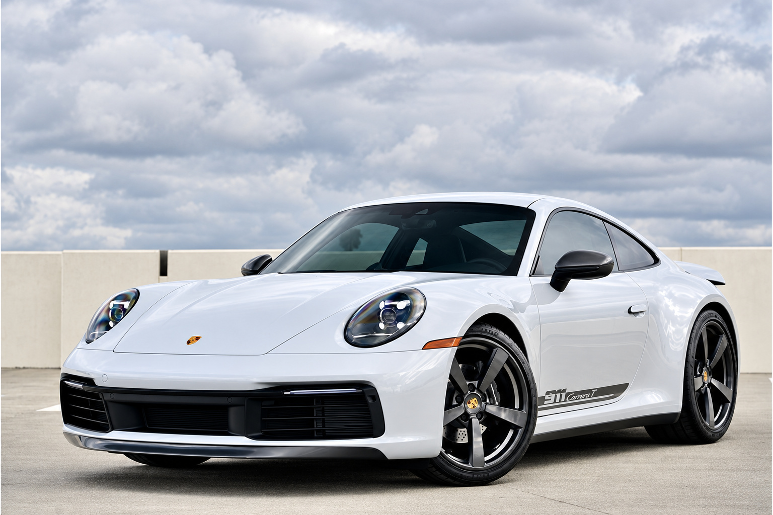 Chalk Porsche 911 Carrera T with black door script on a rooftop deck under an overcast sky, front three-quarter