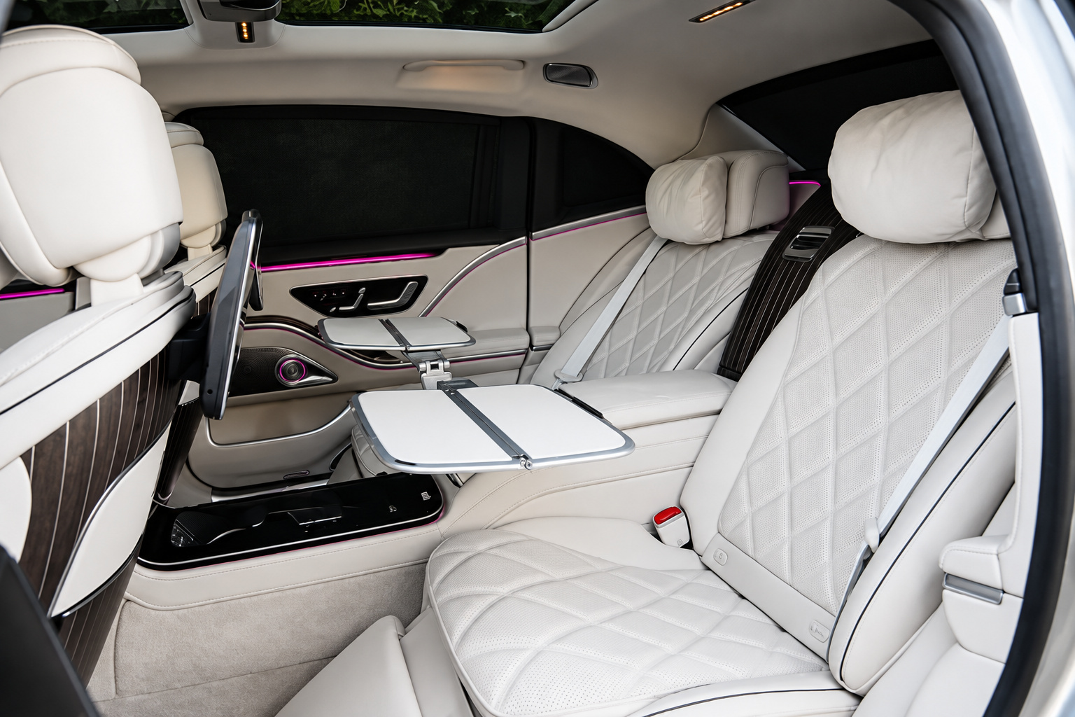 Rear executive seat of the Maybach S580 with the fold-out table open and a screen on the console