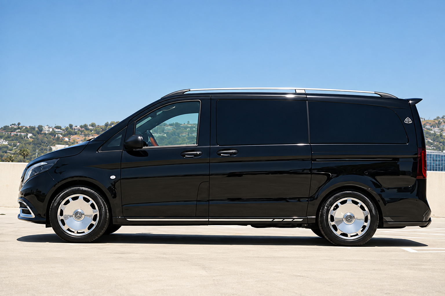 Side profile of the black Mercedes-Benz Sprinter rental on chrome wheels on a rooftop deck