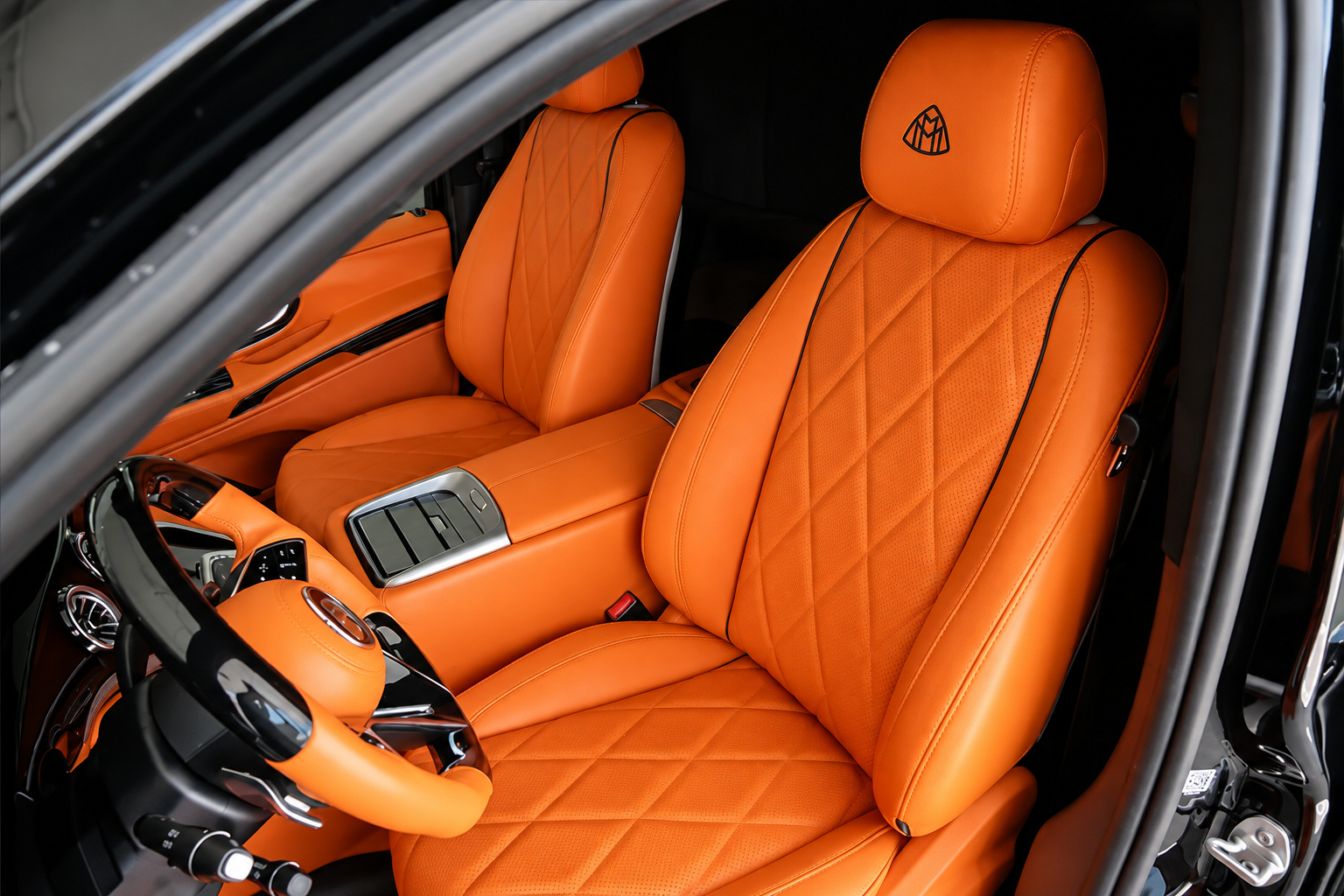 Orange quilted front seat and steering wheel inside the black Mercedes-Benz Sprinter rental