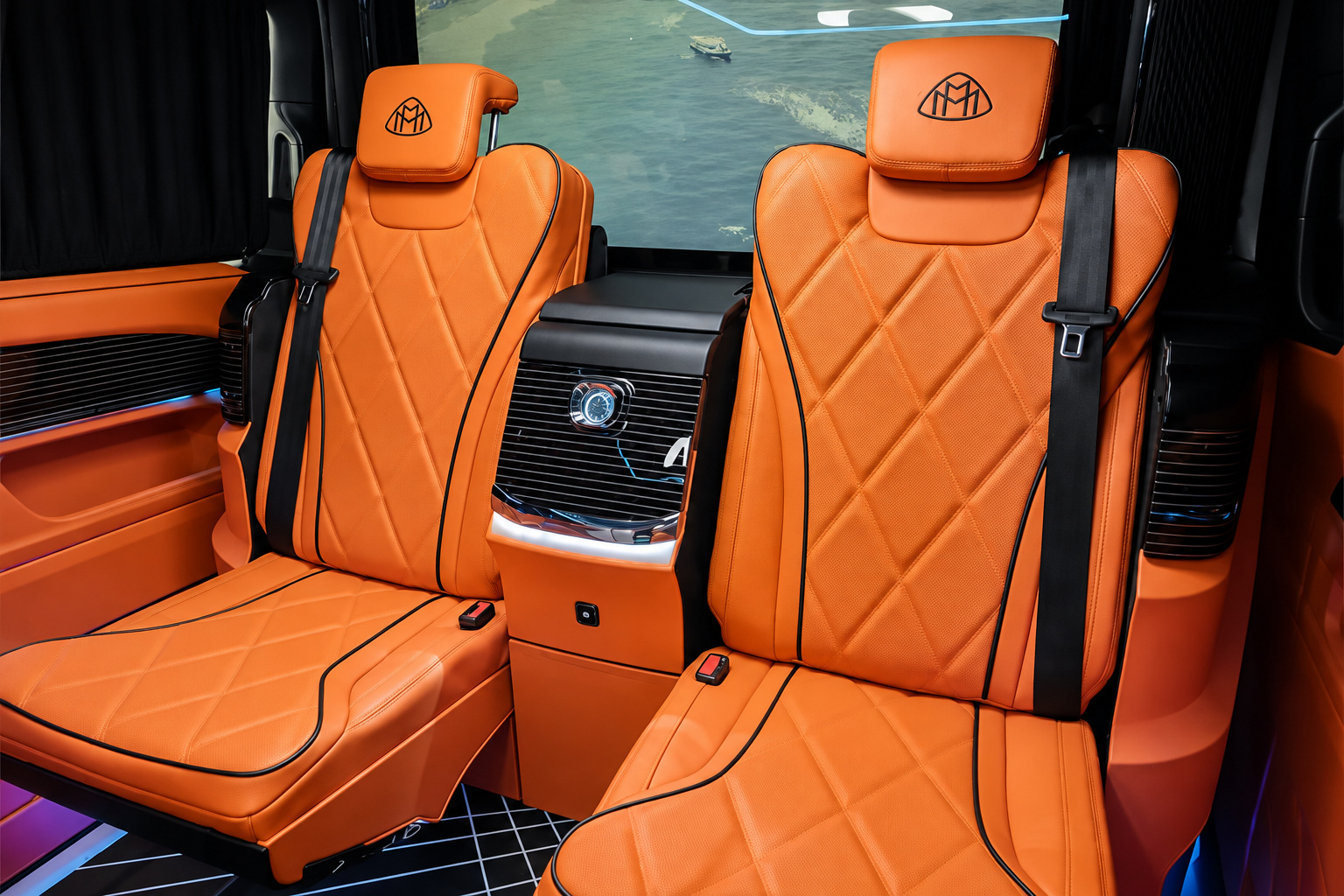 Two orange captain chairs in the Mercedes-Benz Sprinter rental facing the wide screen on the partition