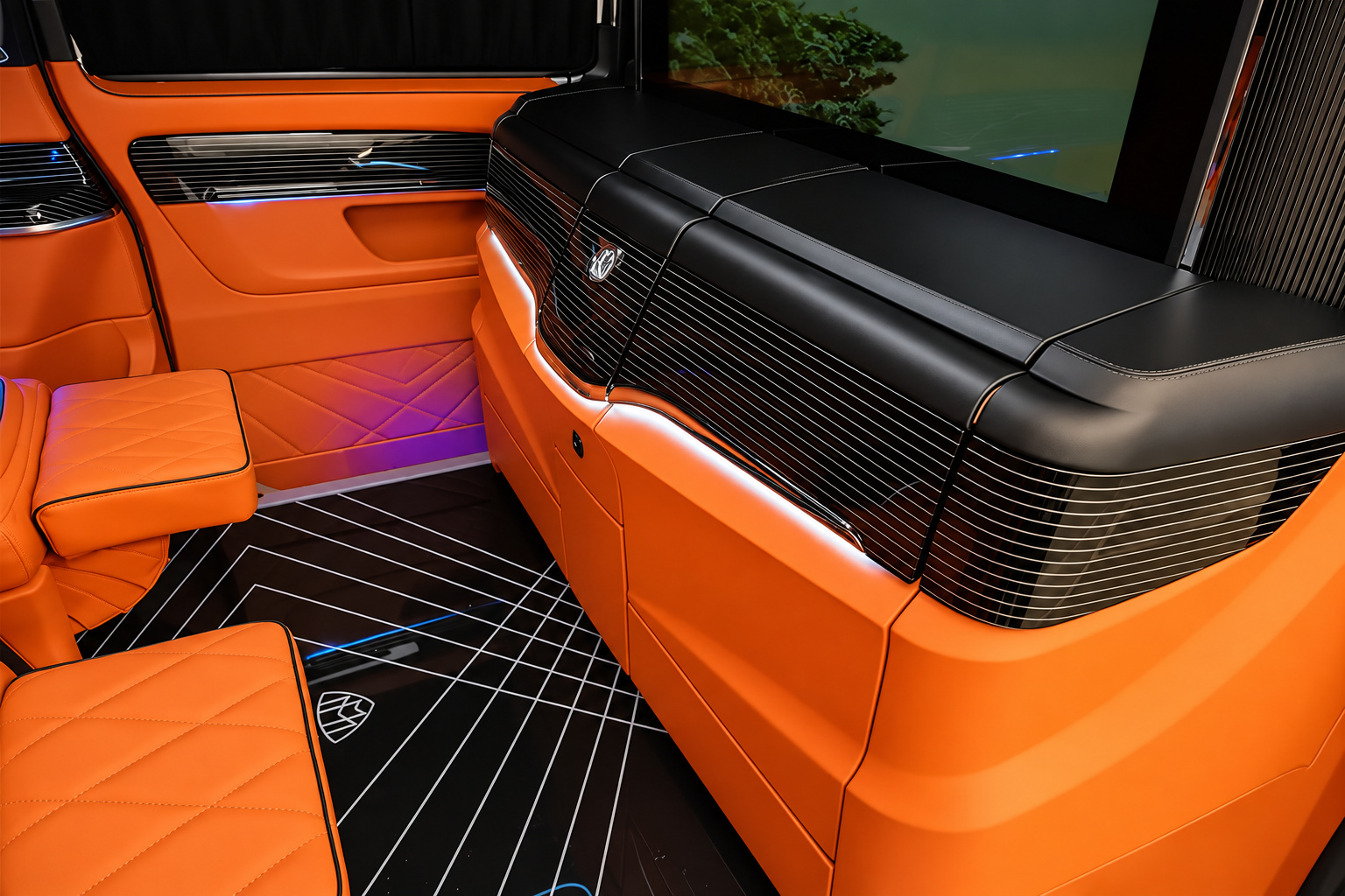 Orange quilted bench seat in the Mercedes-Benz Sprinter rental with ambient lighting along the floor