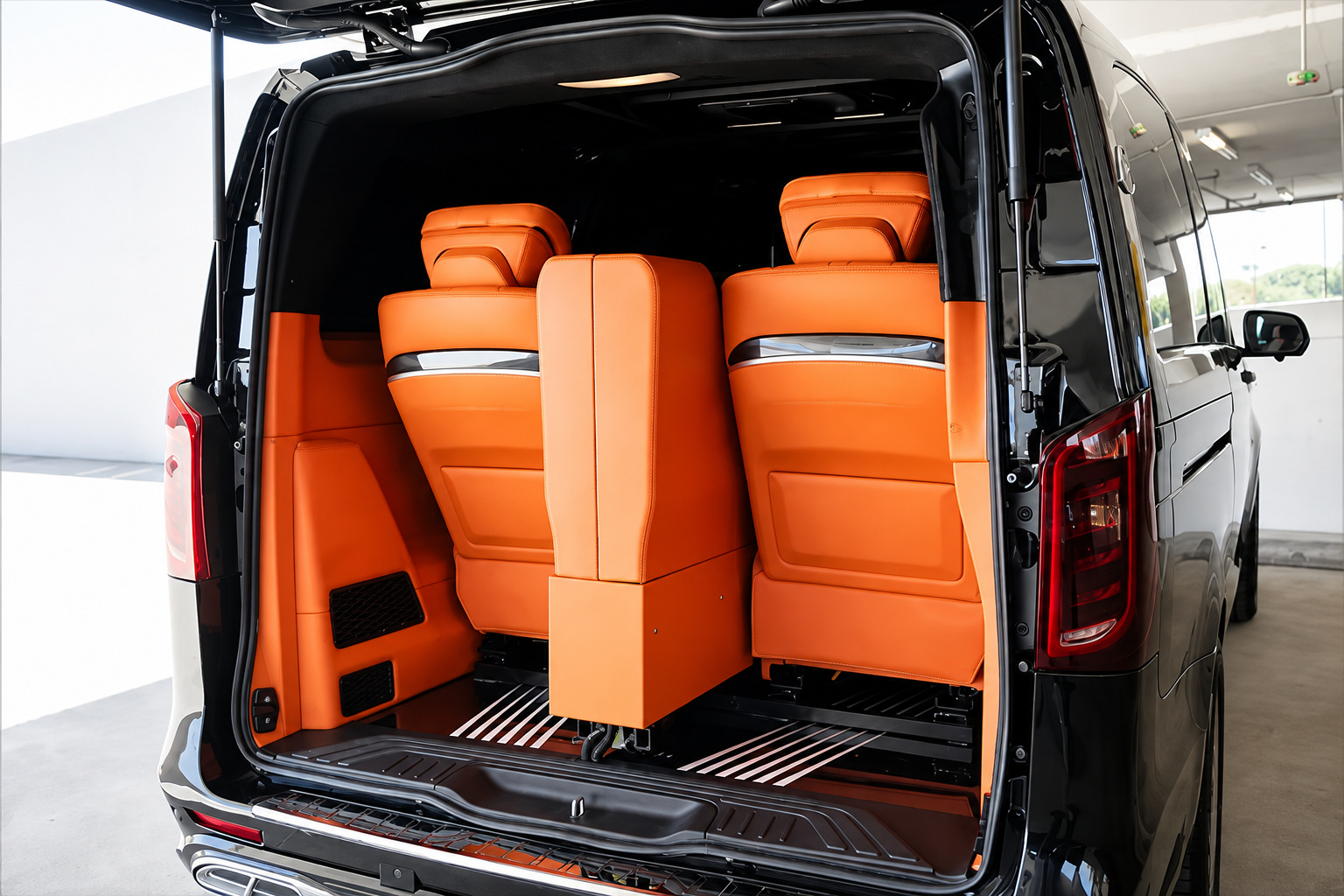 Rear hatch of the black Mercedes-Benz Sprinter rental open, showing the orange bench and the cargo space