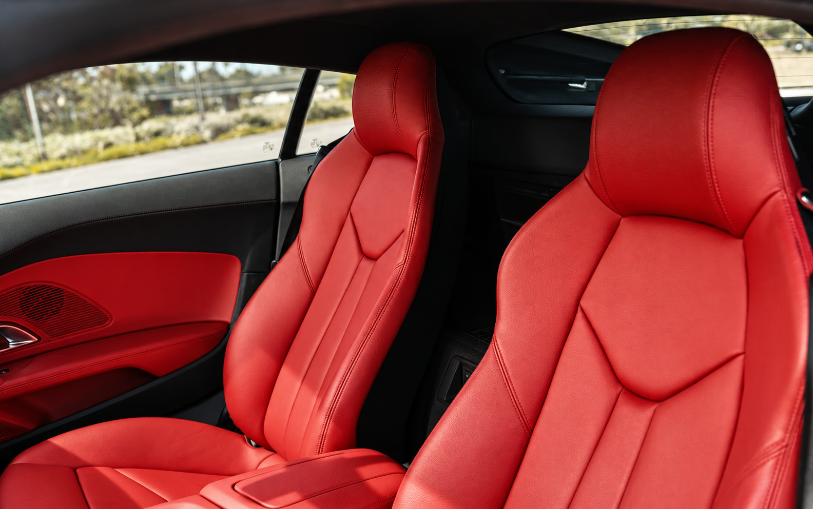 Red leather seats of the Nardo grey Audi R8 V10 Coupe seen through the open passenger door