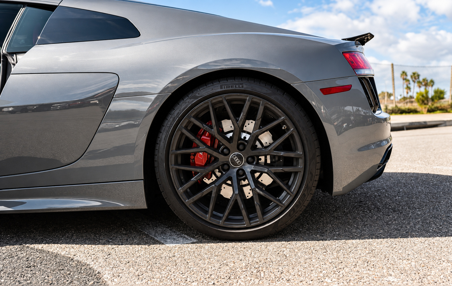 Close view of the R8 V10 Coupe rear wheel, gloss black multi-spoke with a red caliper against the Nardo grey paint