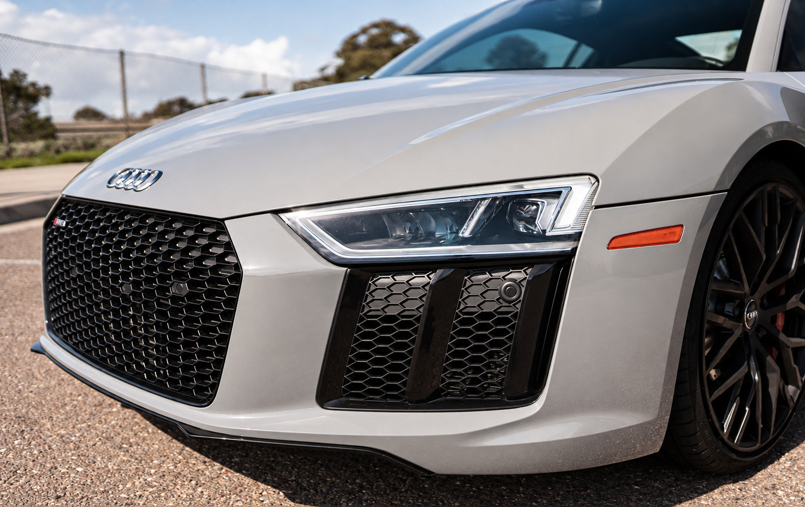 Nose of the Nardo grey Audi R8 V10 Coupe, black honeycomb grille, the Audi rings and the LED headlight up close