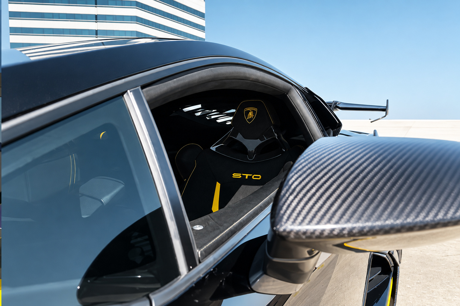 Side glass of the Huracan STO with STO lettering, carbon mirror and the rear wing in the background