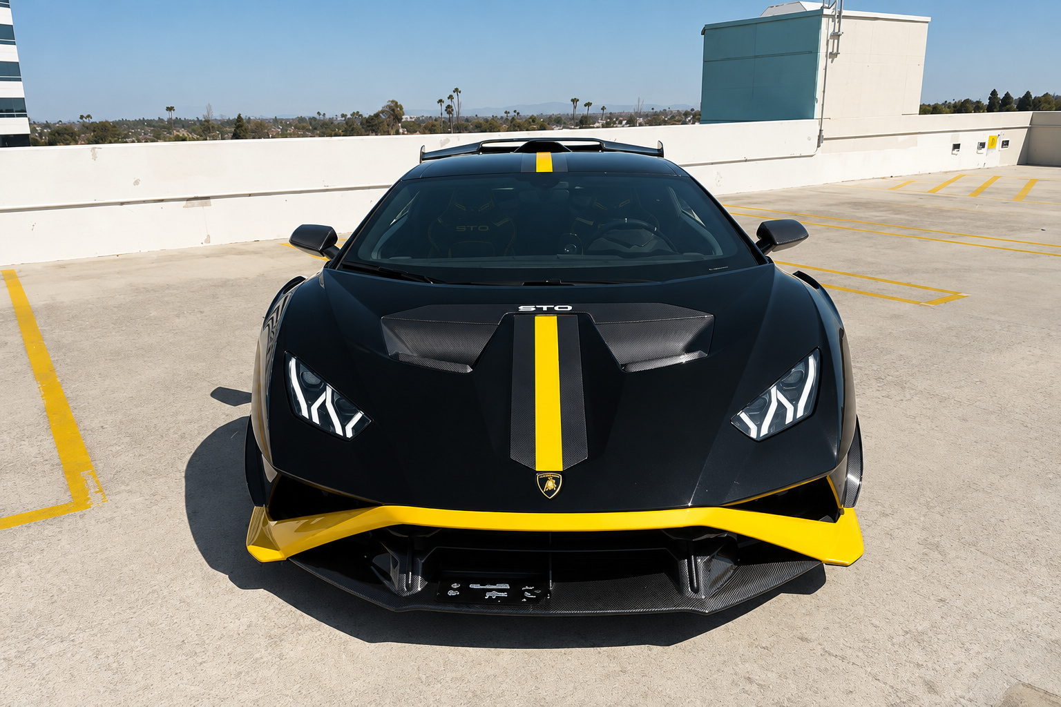 Head-on view of the black Lamborghini Huracan STO with the yellow hood stripe and yellow splitter