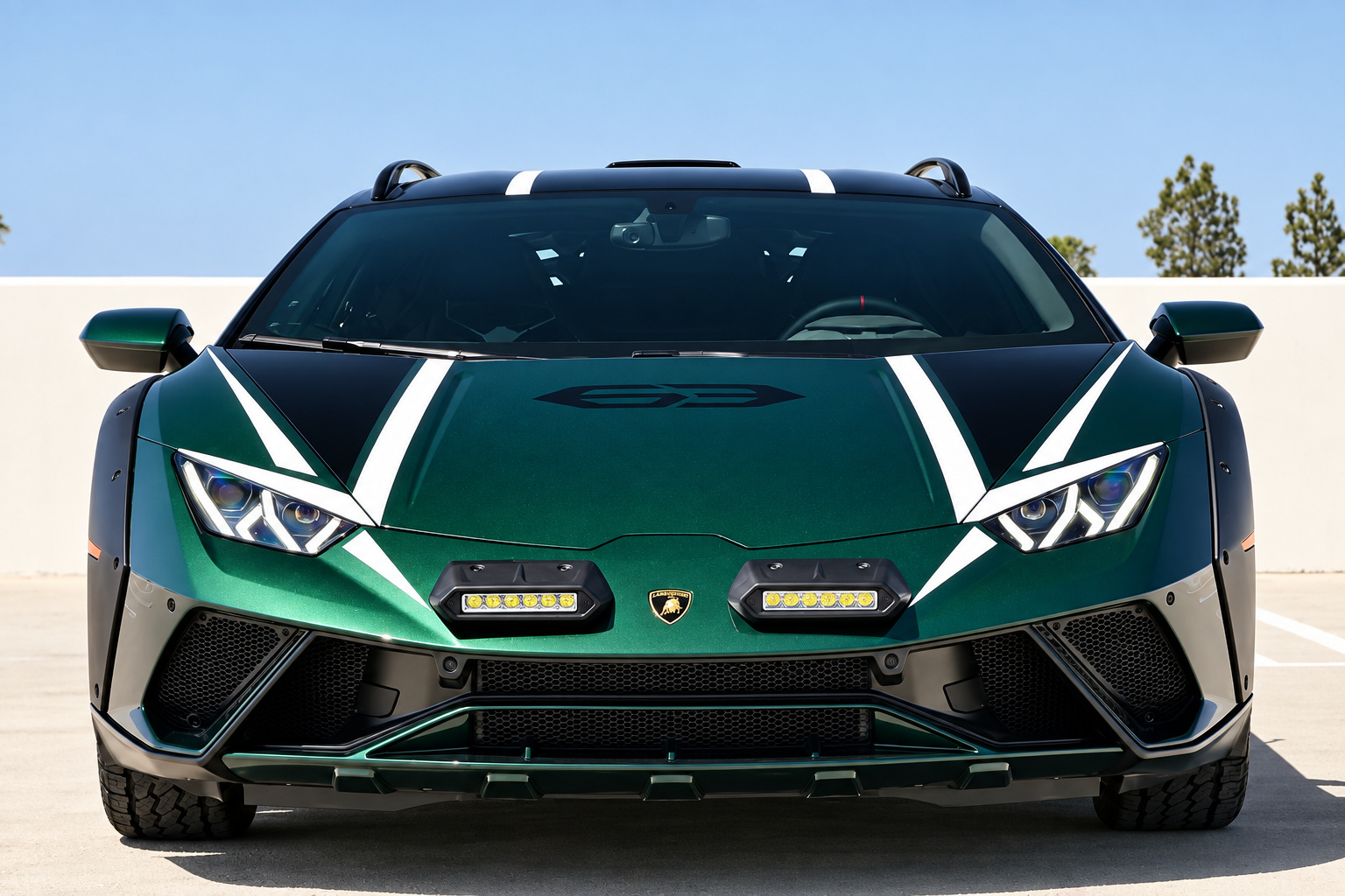 Head-on view of the Huracan Sterrato with white hood stripes, LED light pods in the bumper and the roof scoop