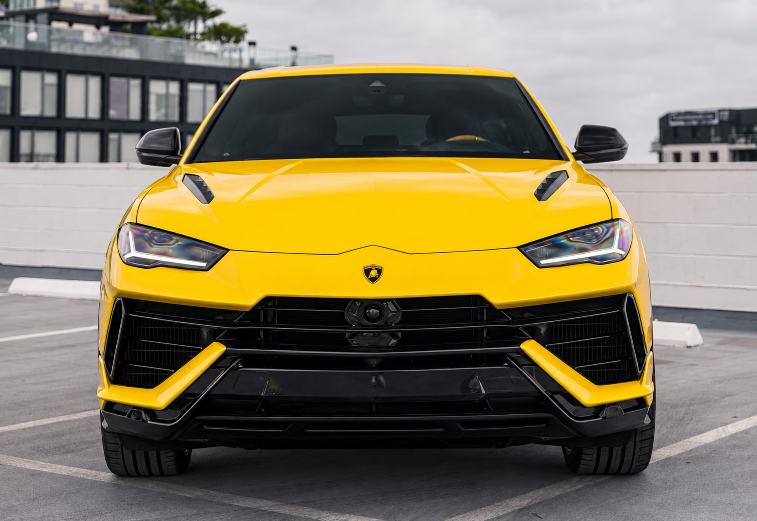 Head-on view of the yellow Lamborghini Urus showing the hood vents, black grille and yellow bumper blades