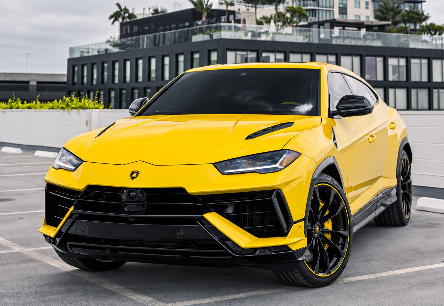 Low front three-quarter of the yellow Lamborghini Urus on the rooftop deck under an overcast sky