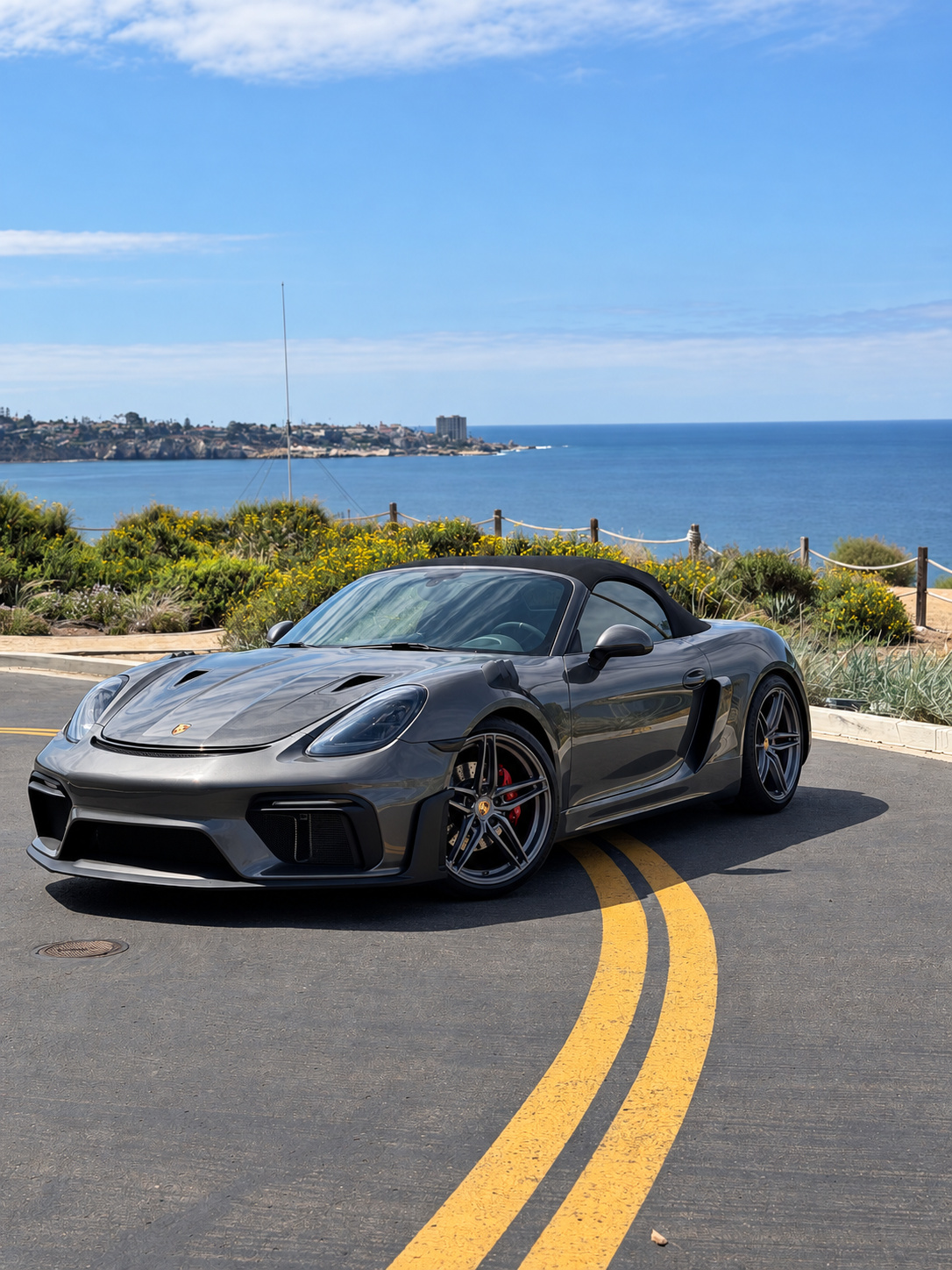 Agate grey Porsche Boxster S with custom RS-style bodywork, top down, on a bend of the La Jolla coast road