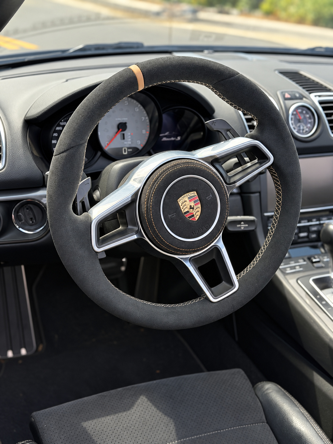 Alcantara steering wheel with a yellow top marker inside the Porsche Boxster S, centre tach behind