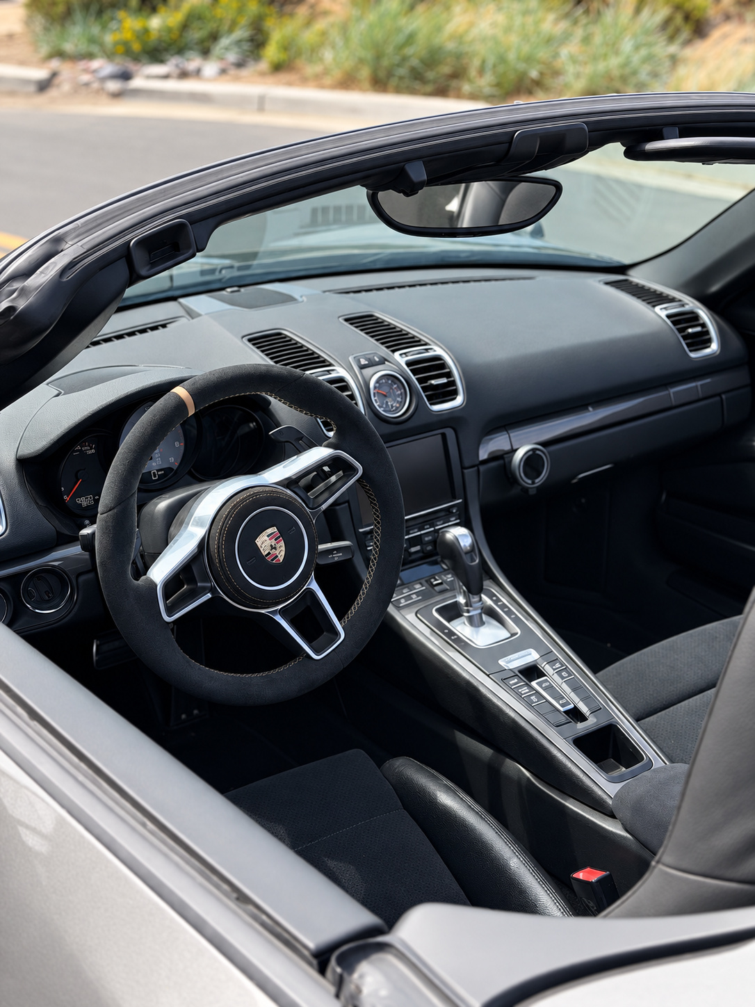 Black alcantara cabin of the Boxster S from the driver's door, PDK shifter and the Porsche crest on the wheel