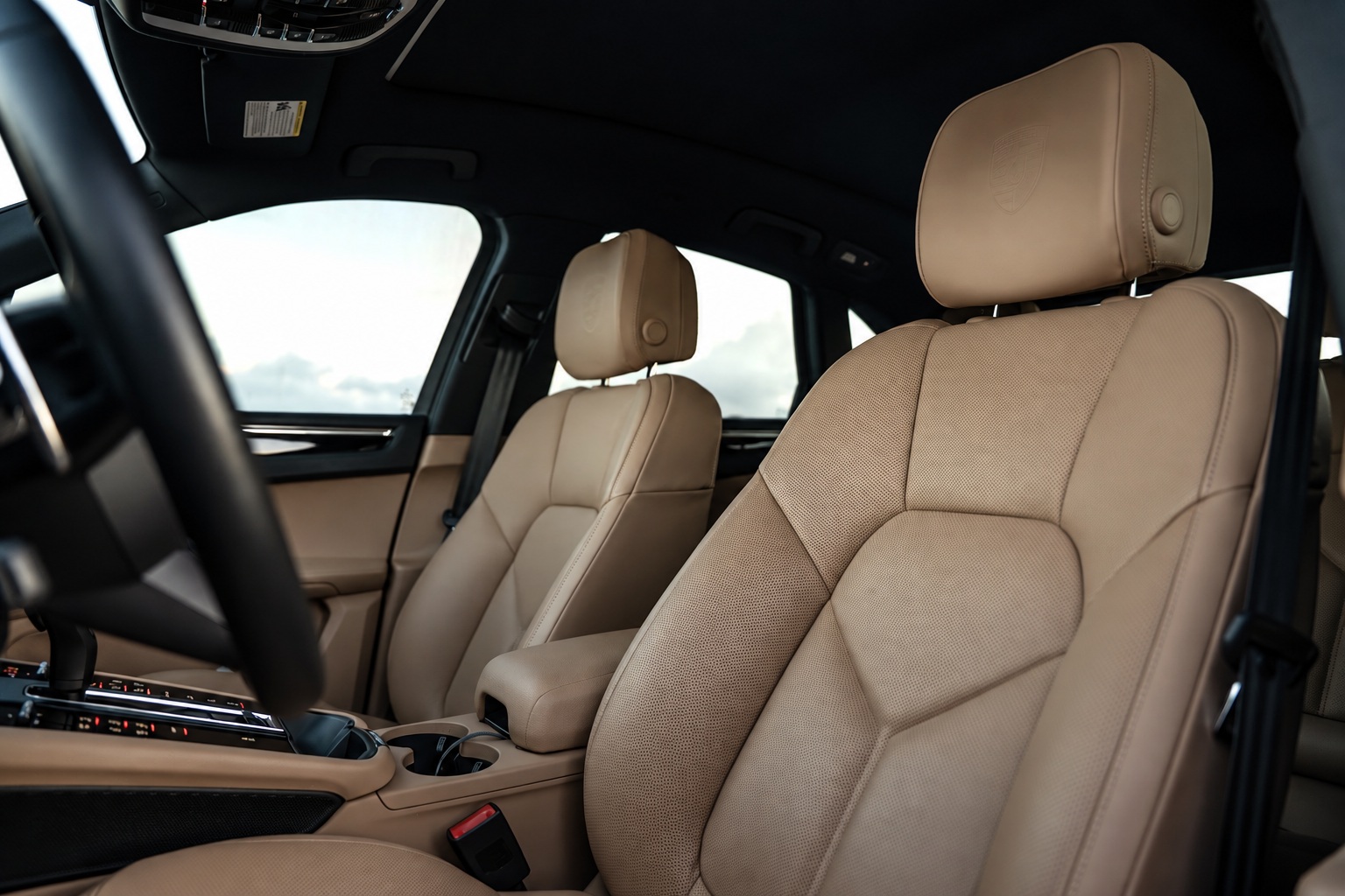 Cream leather front seats of the Porsche Macan seen from the rear door, centre console and shifter