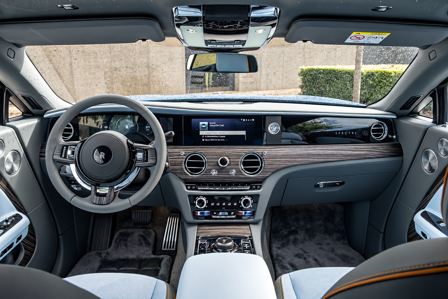 Driver's view of the Rolls Royce Spectre, ivory steering wheel, open-pore wood dash and lambswool carpet