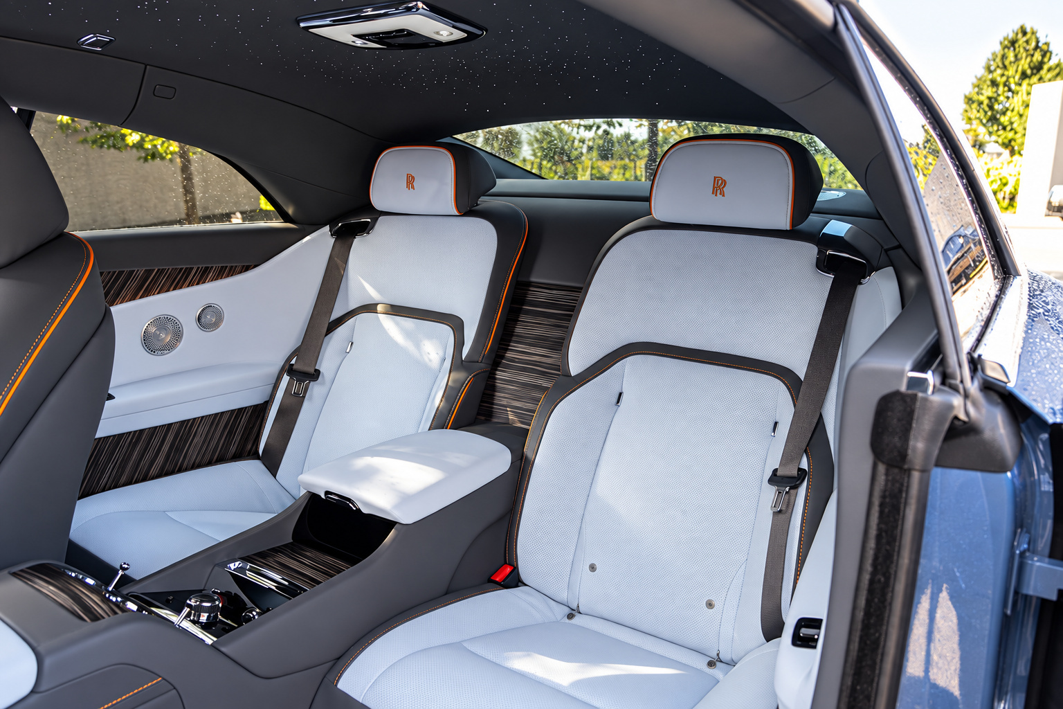 Ivory leather seats inside the blue Rolls Royce Spectre with RR embroidered headrests, seen through the open coach door