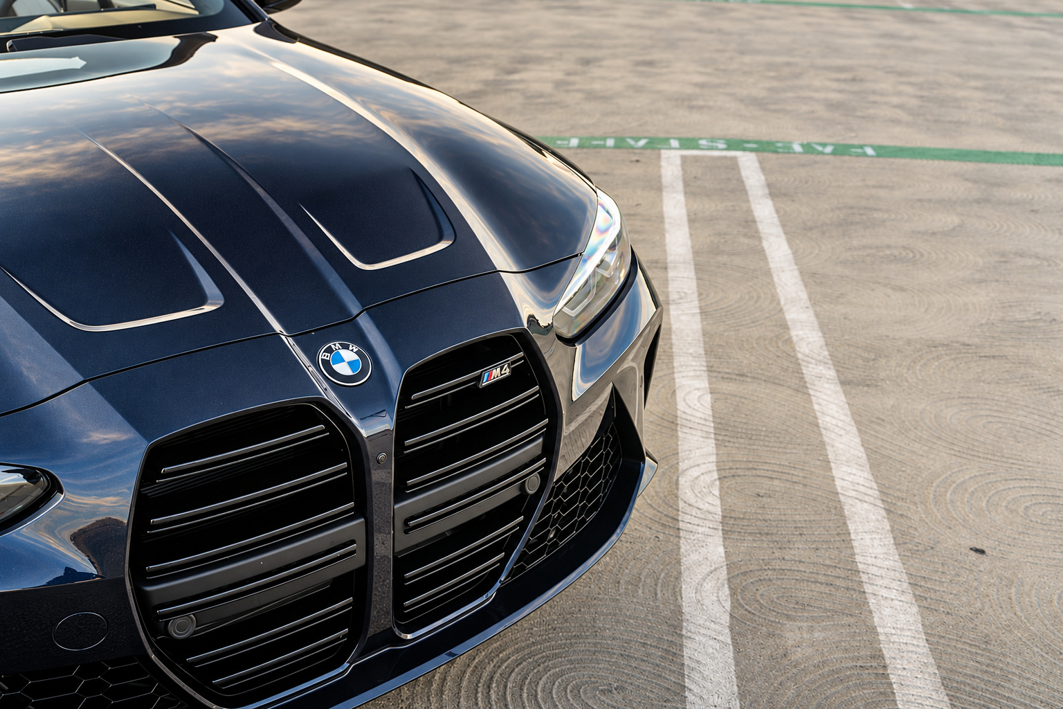 Hood and kidney grille of the black BMW M4 Competition Convertible up close with the M4 badge and headlight