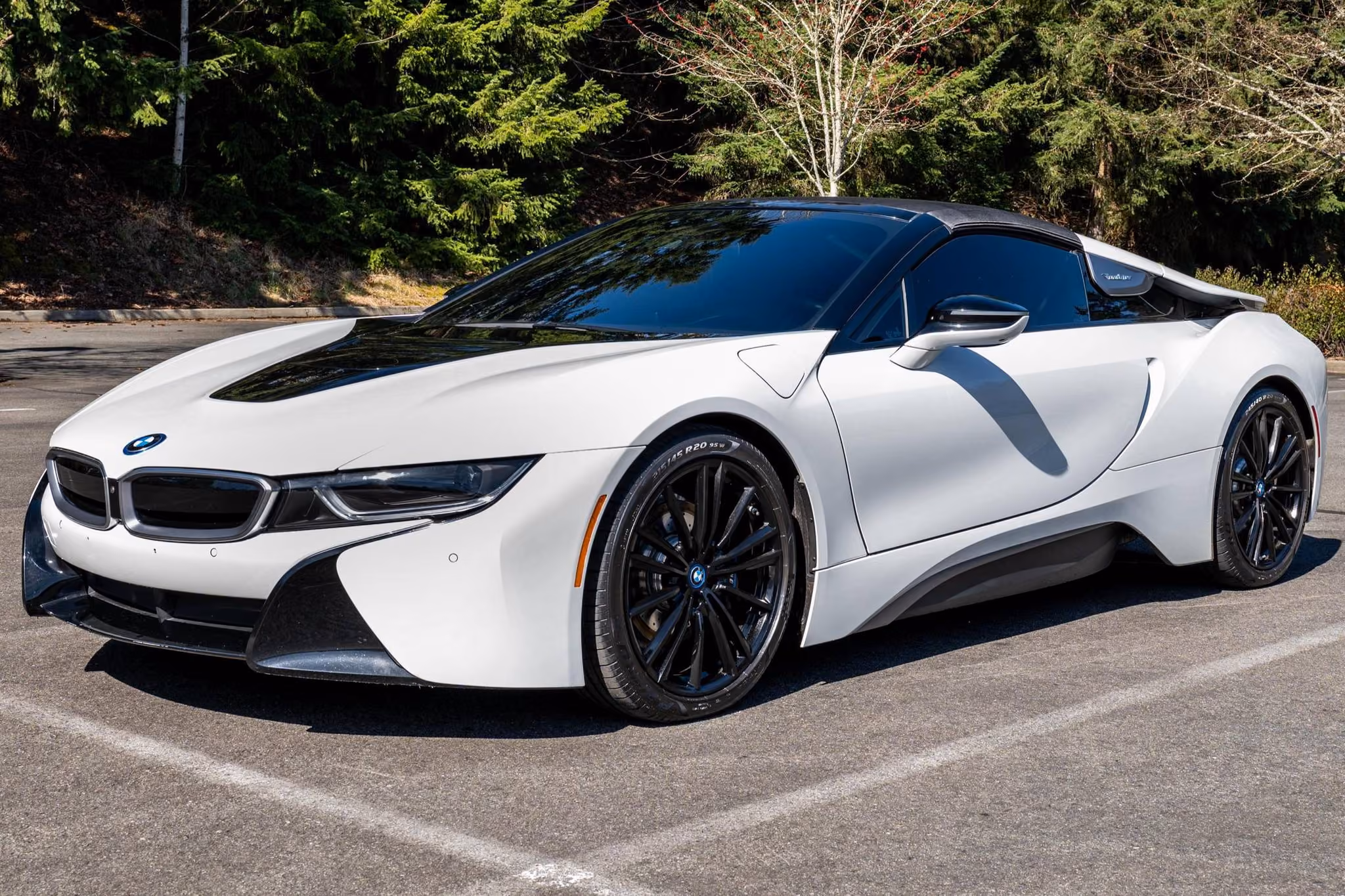 White BMW i8 Coupe with a black roof, black air channels and black wheels, front three-quarter view in a parking lot