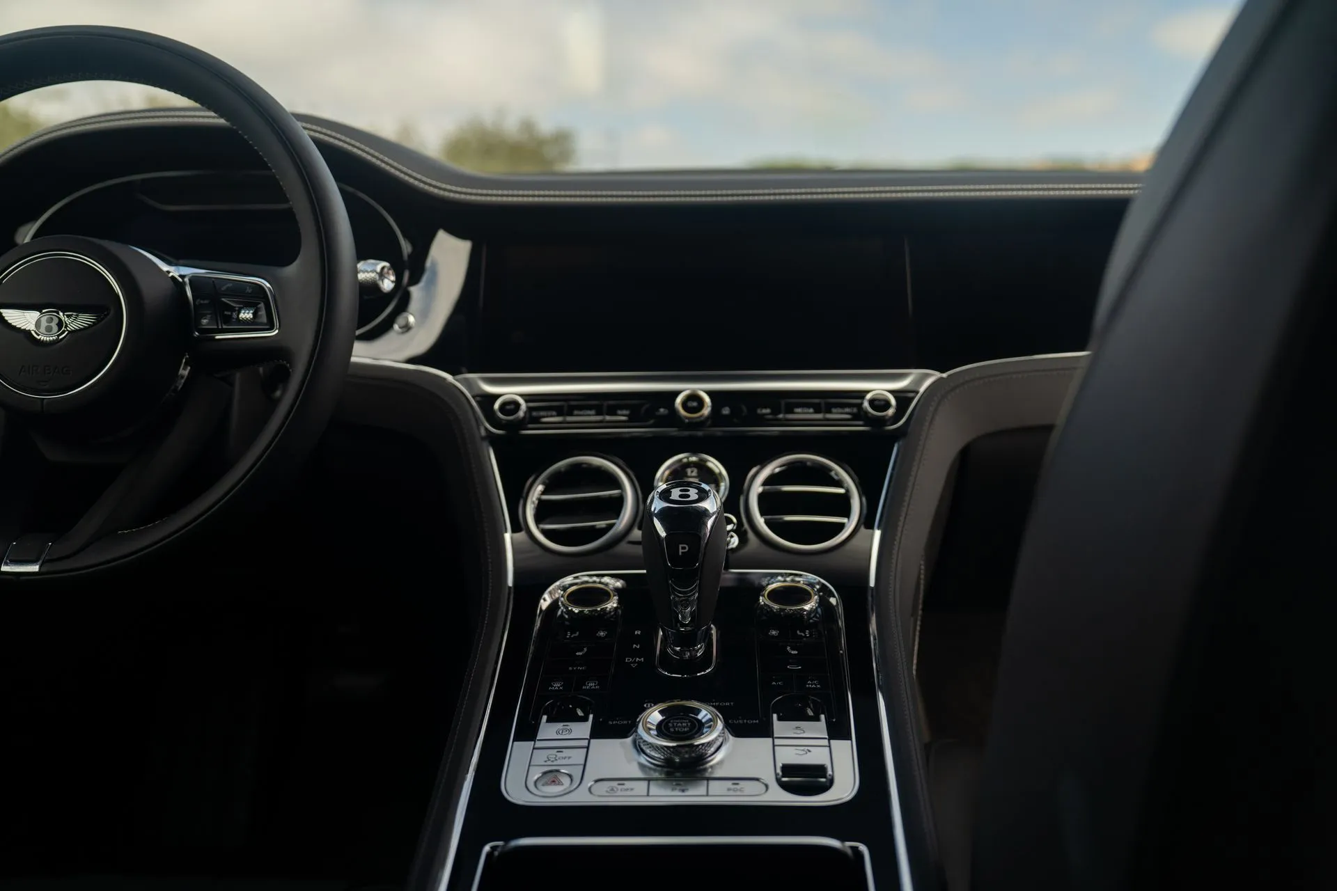 Center dash of the Bentley Continental GT, black leather, dark veneer, organ-stop vents and the knurled drive mode dial