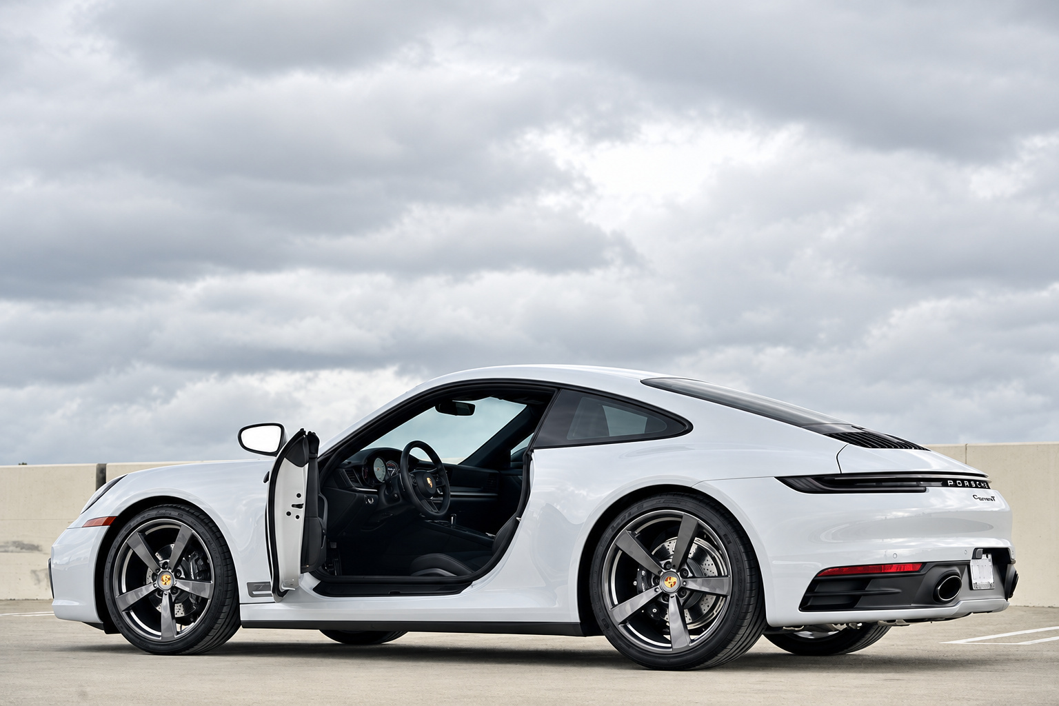 Rear three-quarter of the Chalk Porsche 911 Carrera T with the driver door open on a parking roof
