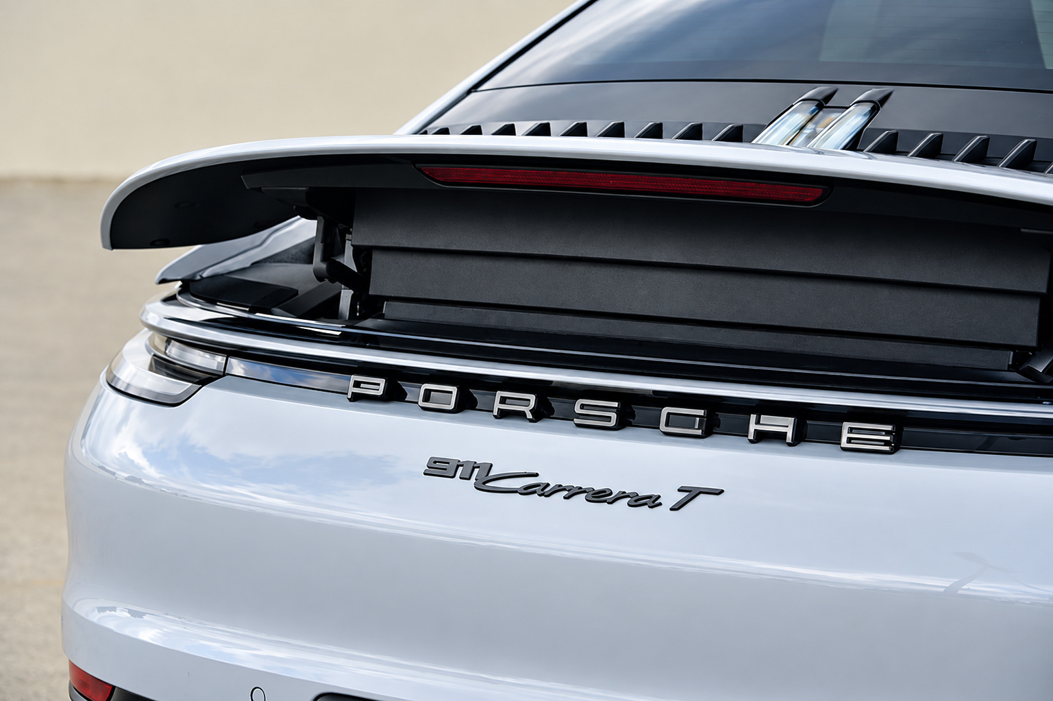 911 Carrera T badge and the raised rear spoiler on the Chalk-coloured tail of the Porsche